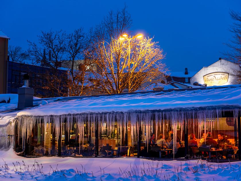 Restauranten i blåtimen, med snø og istapper på taket og varme opplyste vinduer der gjester sitter inne